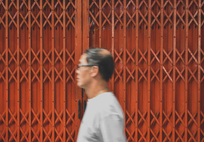 Full length of woman standing by chainlink fence