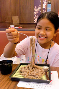 Girl eating noodles on table at restaurant