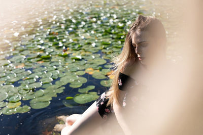 Close-up of young woman sitting by lake