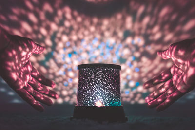 Close-up of hands around illuminated lantern