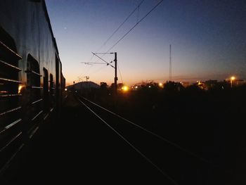 Railroad tracks in city against sky at sunset