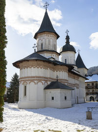 Church by building against sky during winter