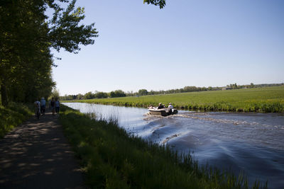 People on boat in river against clear sky