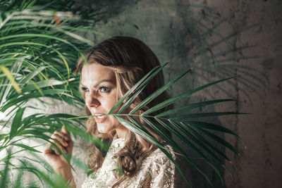 Woman with plant against wall