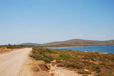 Road leading towards mountains against blue sky