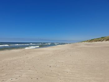 Scenic view of beach against clear blue sky