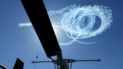 Cropped image of helicopter against vapor trail in sky