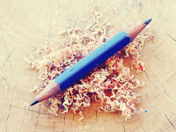 High angle view of blue pencil with shavings on wooden table