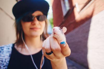 A girl with colored hair holds a rat on the visor of her cap. pets are teenager's friends. 