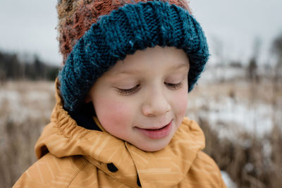 Close up of a young boy looking down smiling whilst playing outside
