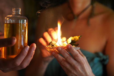 Close-up of hands holding burning candle