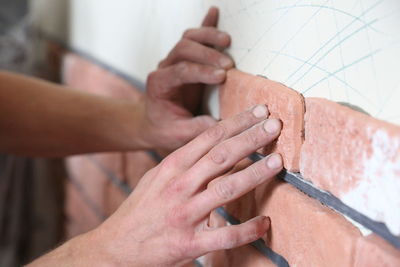 Cropped hands of man making brick wall