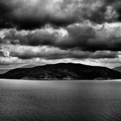 Scenic view of sea and mountains against cloudy sky