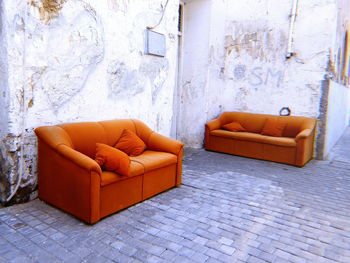 Chair on sofa against orange wall at home