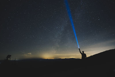 Silhouette man standing against star field at night