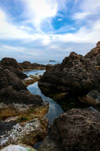 Rock formations on shore against sky