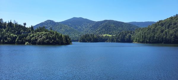 Scenic view of lake and mountains against clear blue sky