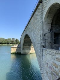 Arch bridge over river against clear blue sky