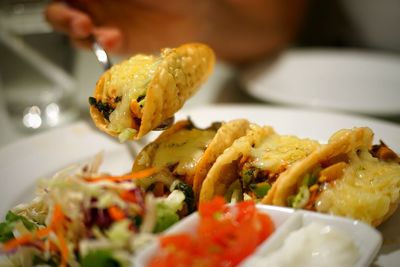 Close-up of hand holding food in plate