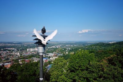 Statue by trees and city against sky