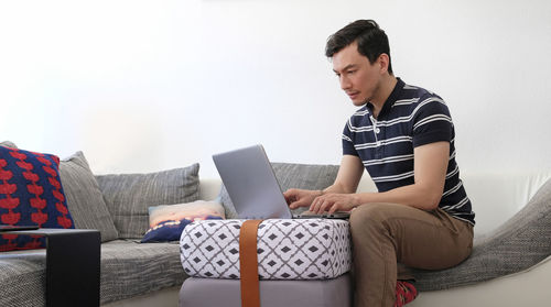 Man using laptop while sitting on sofa at home