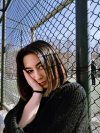 Portrait of beautiful young woman in chainlink fence