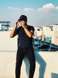 Full length of young man standing against sky in city