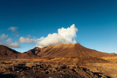 Scenic view of mountains against blue sky