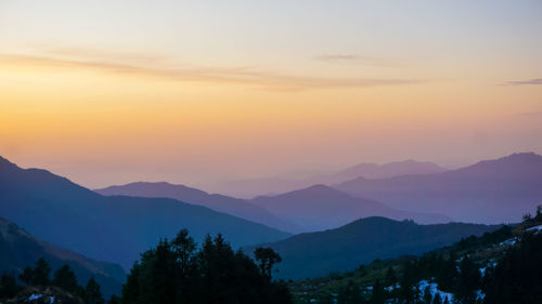 Scenic view of silhouette mountains against orange sky