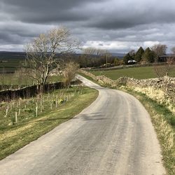 Road amidst field against sky