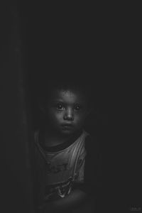 Portrait of young woman against black background