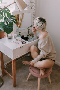 Side view of woman sitting on chair at home