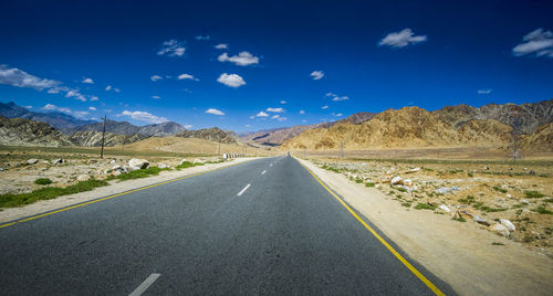 Road amidst landscape against blue sky