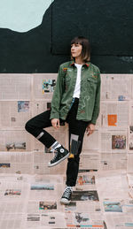 Portrait of young woman standing against building in city