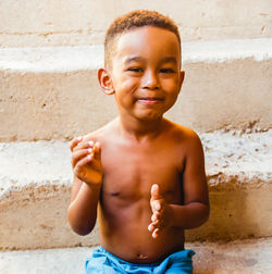 Portrait of shirtless boy standing against wall