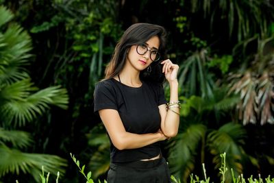 Young woman standing against plants