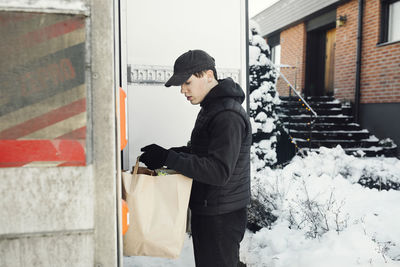 Man unloading grocery from car trunk