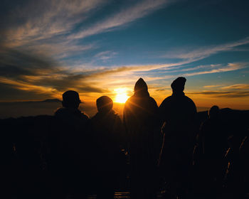 Silhouette people on mountain against sky during sunset