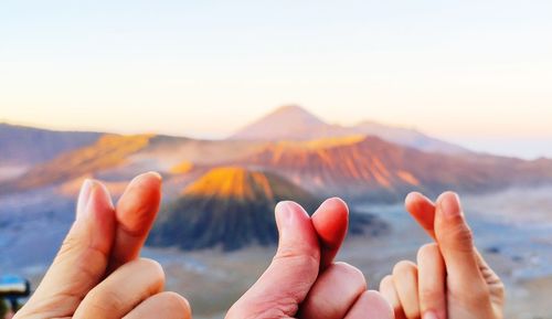 Cropped hands of people gesturing against clear sky