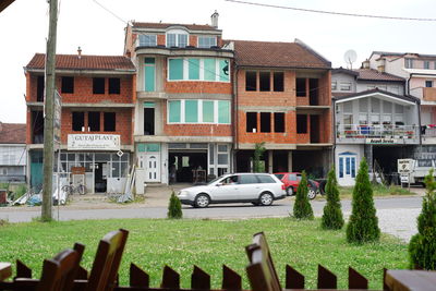 Cars on street by buildings against sky