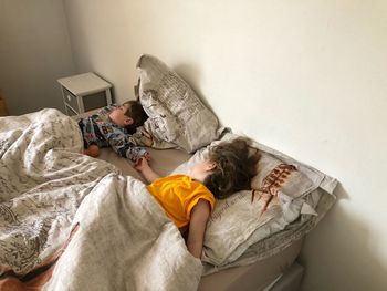 Cute siblings sleeping on bed at home