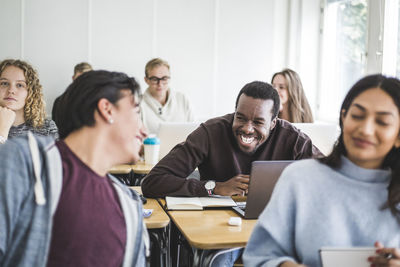 Cheerful male friends talking in classroom