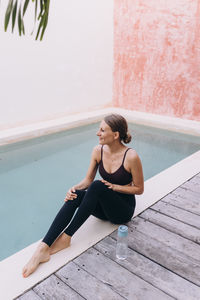 High angle portrait of woman in yoga clothes next to a pool in tulum, mexico