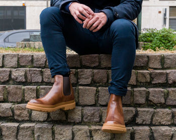 Low section of man sitting on concrete footpath