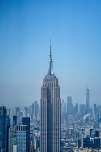 Buildings in city against clear blue sky