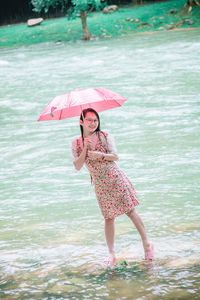 Full length of a woman with umbrella in rain