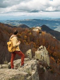 Traveler stands and enjoys the view from hilly viewpoint. traveling on hill peaks landscape
