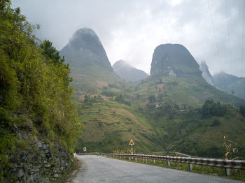 Road amidst green mountains against sky