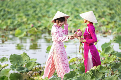 Woman with pink umbrella standing against plants