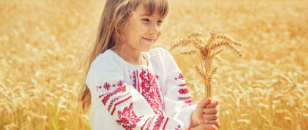 Cute girl with wheat standing at farm